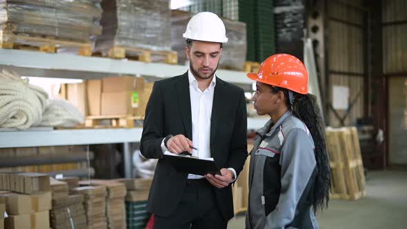 A young manager and a warehouse worker discuss the availability of goods