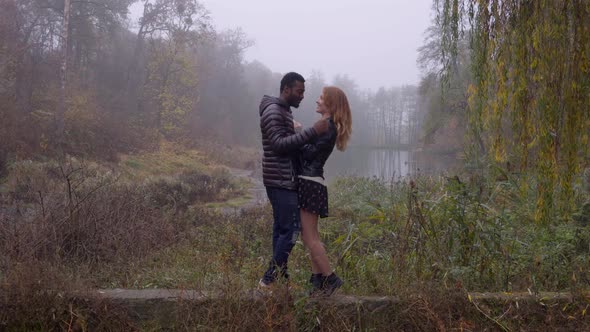 Interracial Love Concept. Beautiful Young Interracial Couple Posing in the Foggy Autumn Park