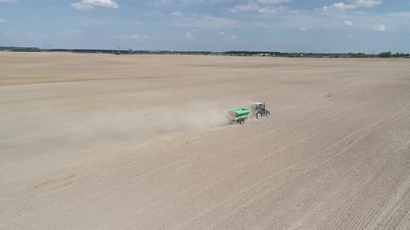 Aerial View  Video of Tractor with Fertilizer Trailer Fertilizes the Field After Planting