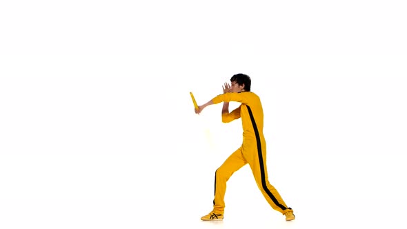 Man in Yellow Suit Training Karate and Expertly Twirling Nunchaku