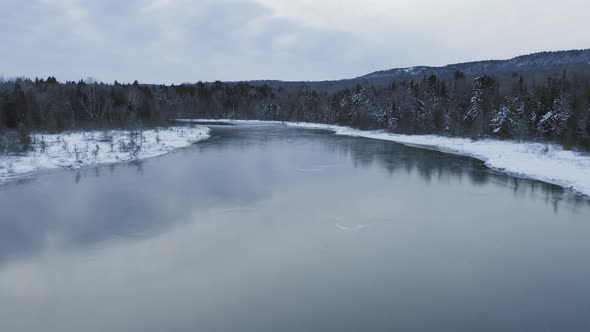 Aerial flight down frozen river Winter wonderland