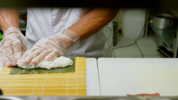Male chef preparing rice roll in kitchen