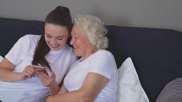 Woman Teaching Grandmother How To Use Smartphone