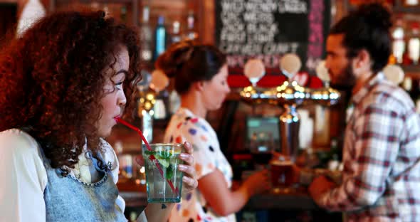 Beautiful woman looking at couple while having cocktail