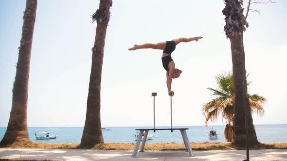 Gymnastics By the Sea  a Young Blonde Woman Training on the High Small Beams  Doing a Handstand