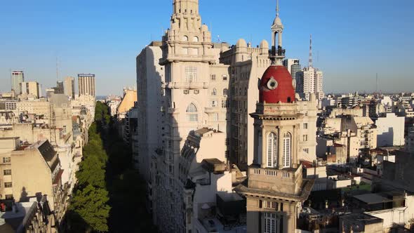 Aerial dolly out of Barolo Palace tower and Buenos Aires buildings on tree-lined Avenida de Mayo at