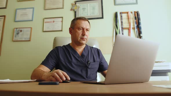 Portrait of Handsome Adult Busy Caucasian Male Doctor Sitting at Desk in