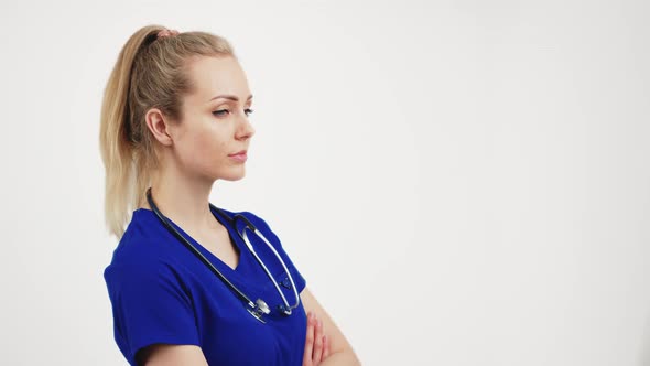 Blonde Beautiful Nurse Stands Facing the Camera with Her Hands Folded Isolated White Background