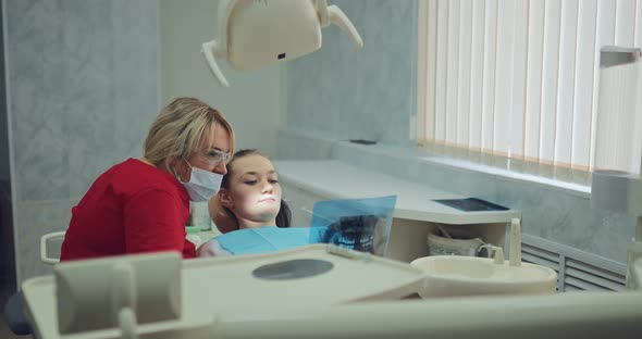 Beautiful Female Dentist Looking at an Xray Picture with a Patient