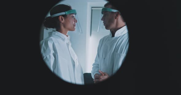 Two doctors wearing a visor, talking in a medical laboratory