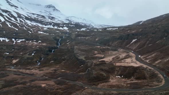 A Car Drives Along The Asphalt Road Near Klifbrekkufossar Waterfall In Eastern Iceland. Aerial Wide