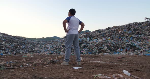 Young Boy Stands And Looking At Garbage Pile