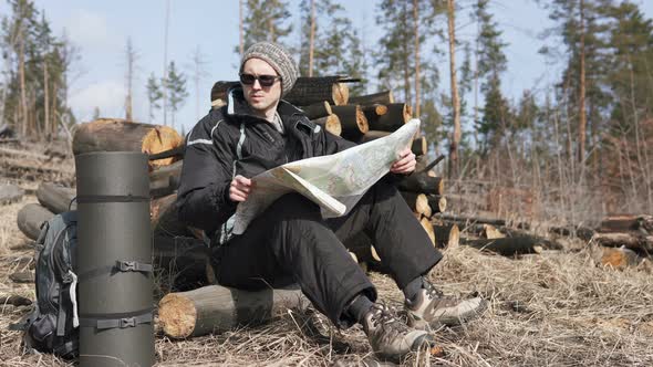 Orienteering in the forest. Tourist on a hike in a forest park with a map.