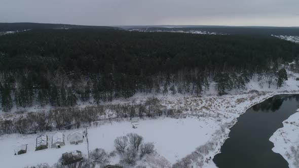 Aerial view of winter river near the forest. In the far village. Mainly cloudy 01