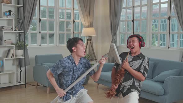 Young Asian Father And His Son Have Fun Singing Together At Living Room