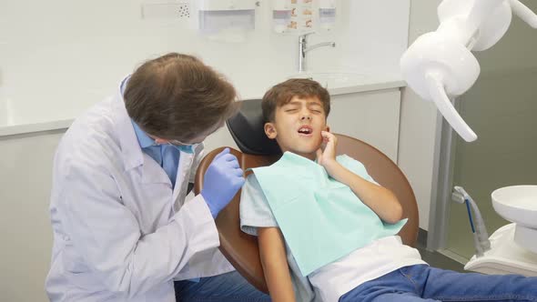 Little Boy Having Tootache, Sitting in Dental Chair During Teeth Examination