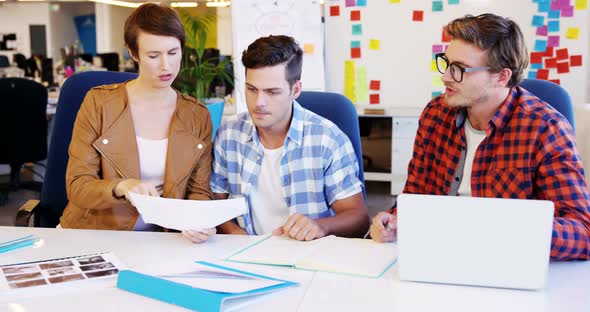 Graphic designer holding photo sample and interacting with colleagues