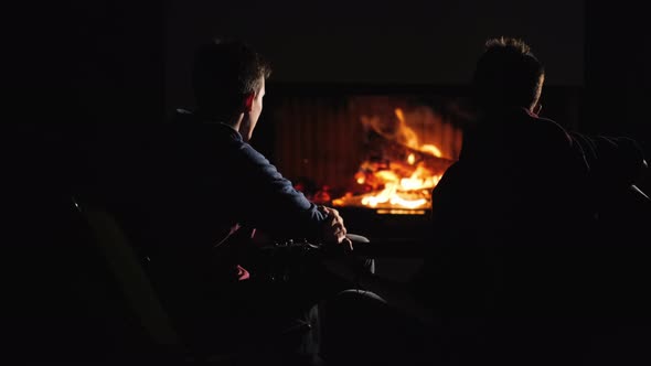 Two Guys are Smothering By the Fireplace Playing the Guitar