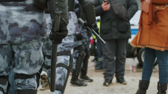 Casually Walking Police Officer in Riot Gear Uniform Holding Baton in Hands