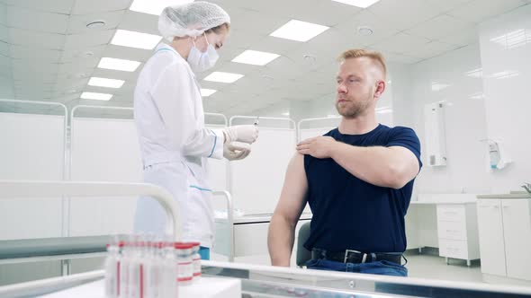 A Man is Getting Vaccinated By a Medical Worker