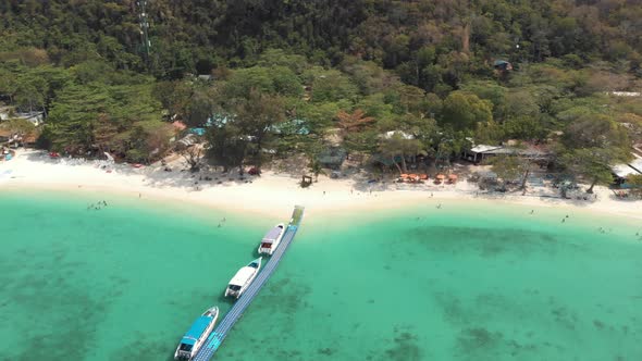 Banana Beach Pier across shallow emerald Sea with tourists tour boats in Koh Hey, Thailand