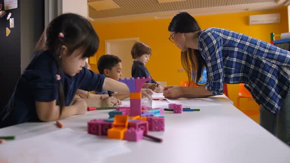 Teacher Working with Creative Kids in Kindergarten