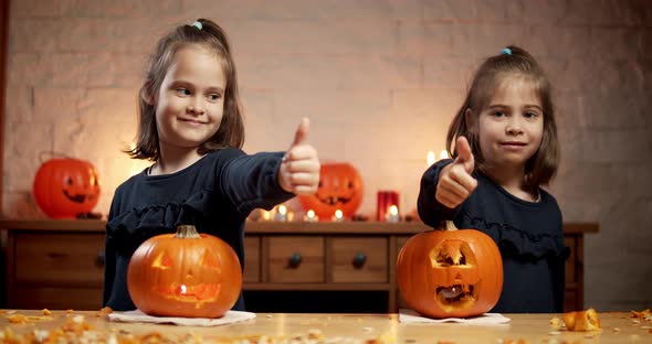 Two Cute Little Girls Are Cutting a Pumpkin on the Table for Halloween