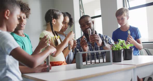 Video of happy african american male teacher and class of diverse pupils during biology lesson