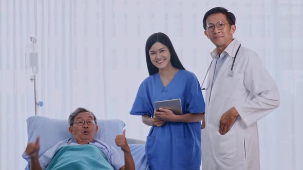 Doctor and physiotherapist talking to elderly patient lying on bed