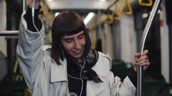 Portrait of Young Woman Wearing in Coat with Headphones Listening To Music and Funny Dancing in