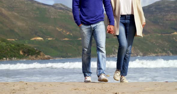 Mature couple holding hands and walking on the beach