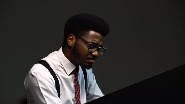 Handsome African American Man in a Stylish Suit and Glasses Sings and Composes Himself on the Grand