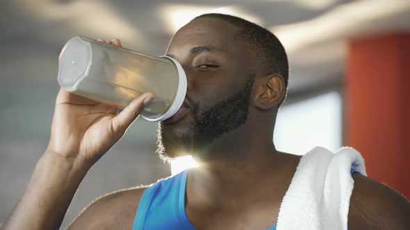 Sexy Athletic Man Drinking Protein Cocktail and Looking Seductively Into Camera