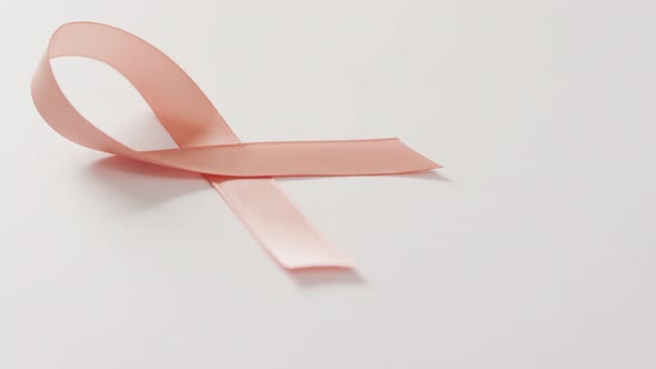 Video of peach pink uterine cancer ribbon on white background