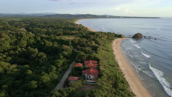 Drone orbiting around beach front resort at Playa Ventanas near Tamarindo, Costa Rica. 90 degree cir