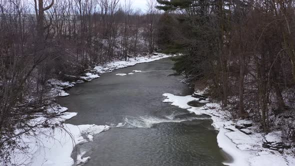 icy winter river between forest closeup along the water