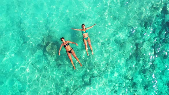 Pretty smiling girls travelling having fun at the beach on summer white sand and blue background 4K