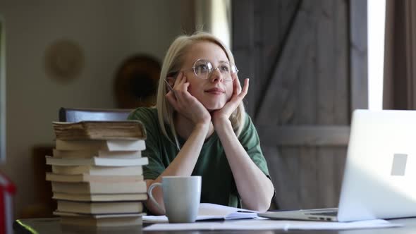 Blonde girl in glasses working with notebook at home as freelancer