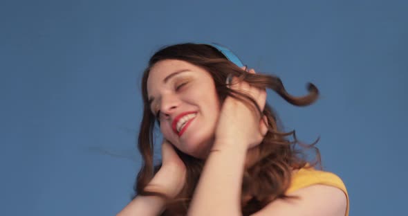 Young Girl in Yellow Shirt and Headphones Listening Music