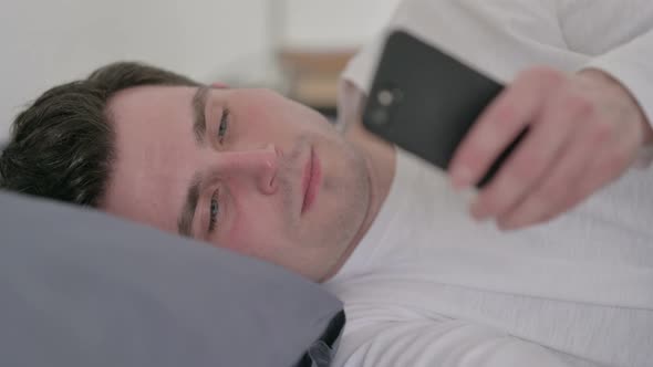 Man Using Smartphone While Sleeping in Bed Close Up