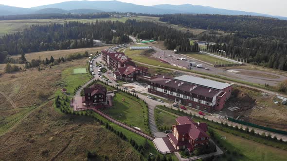 Drone is flying over biathlon sports base in green pine trees mountains