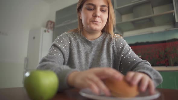 Close Up Apple and Burger Lying in Front of Chubby Girl