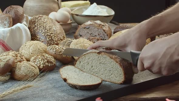 Hands Cutting the Baked Dutch Bread on the Table