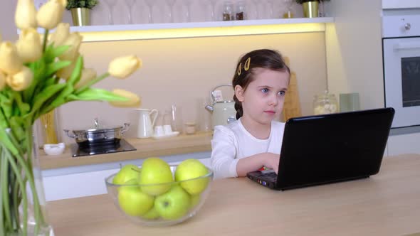 Little Caucasian Girl Has Video Call in Remote Class with Teacher Using Laptop