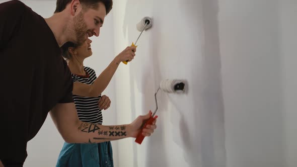 Tracking video of caucasian couple painting wall in new house. Shot with RED helium camera in 8K