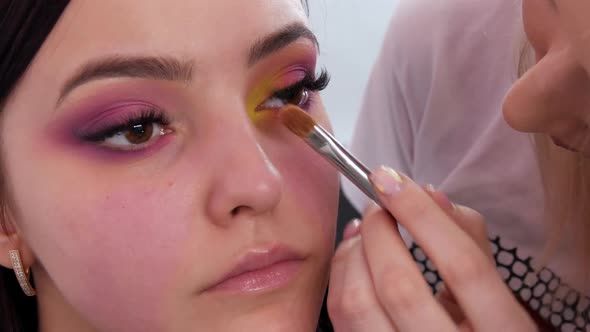 A Professional Makeup Artist Applies Yellow Eyeshadow with a Special Brush in a Makeup Studio