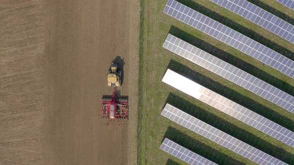 New and Old Farming as a Seed Drill Works Alongside a Solar Power Farm