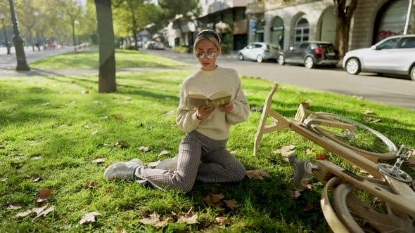 Happy Stylish Woman with Wooden Eco Bicycle Reading a Book