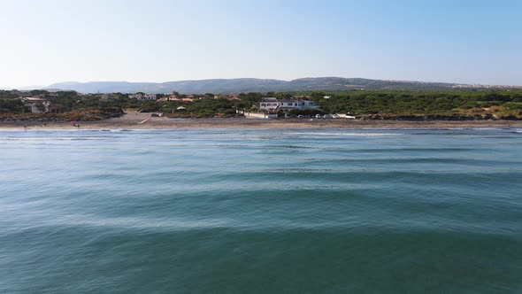 Tracking aerial panoramic drone view of coastline and nearby village in Sardinia, Italy