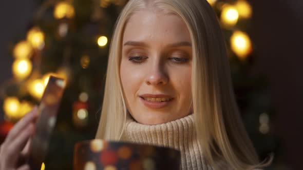 A Young Beautiful Woman Is Opening a Gift Box Light Shines on Her Face